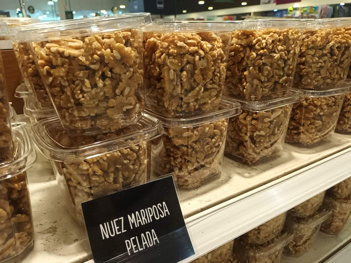 Potes transparentes con nueces mariposa peladas en exhibición, fruto seco energético para gallinas