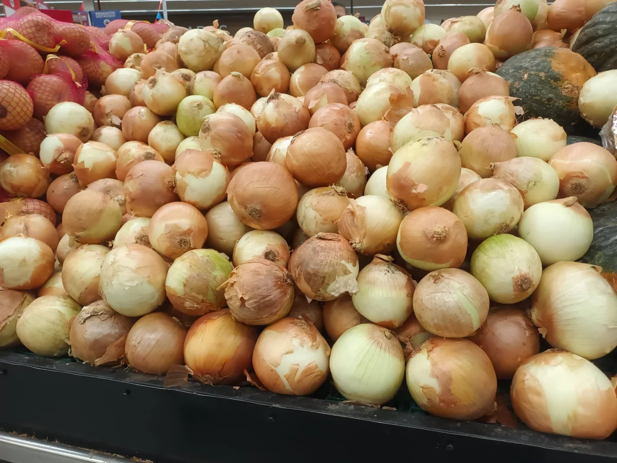 Cebollas amarillas apiladas en la verdulería de un supermercado